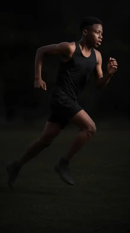 An athlete sprinting across a pitch at dusk